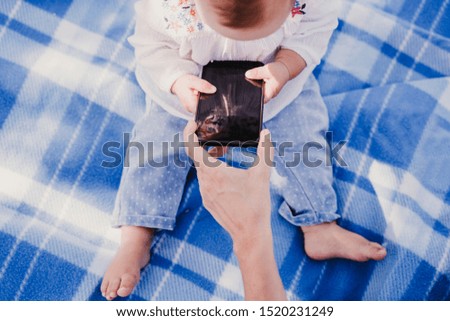 baby girl outdoors in a park using mobile phone, happy family concept. love mother daughter