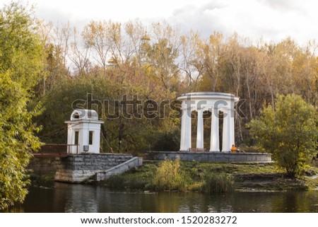 Old park in the fall. View of the island with a white rotunda and an arch.