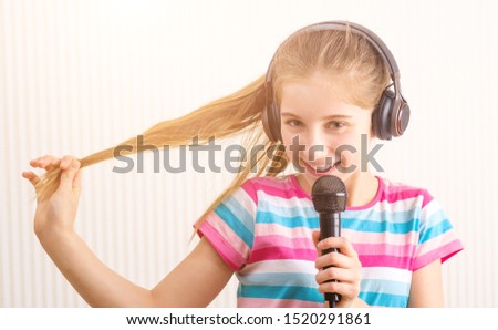 Smiling girl in headphones holding microphone in studio