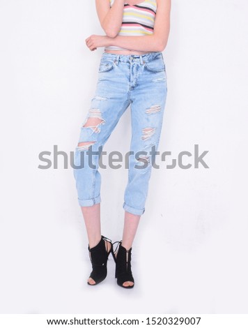 women in striped sweater with torn jeans with black high hell shoes posing