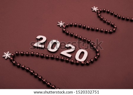 2020 is lined with wooden figures. The figure of the Christmas tree is lined with beads. happy New year