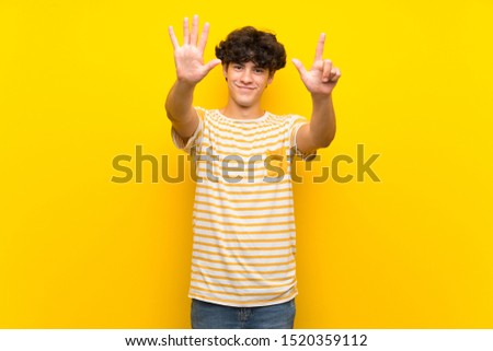 Young man over isolated yellow wall counting seven with fingers