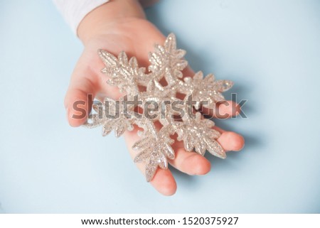 Girl's hand holding a Christmas decor big snowflake in a hands on the blue background