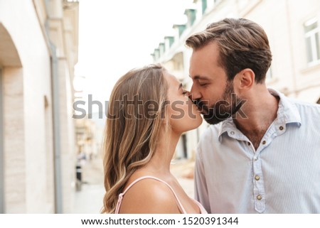 Close up of a happy beautiful couple embracing while standing at the city street, kissing
