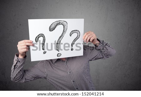 Businessman holding a paper with drawed question marks on it in front of his head