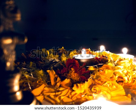 close up view of diwali diya decor with yellow and red marigold flower and defocus brass pital bell ghanta enhance the beauty in dark background