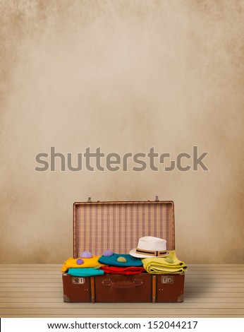 Retro tourist luggage with colorful clothes and copyspace on grungy background