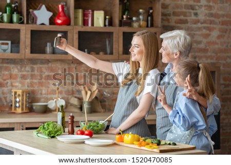 Daughter, mom and granny taking selfie while making healthy dinner together, side view, copy space