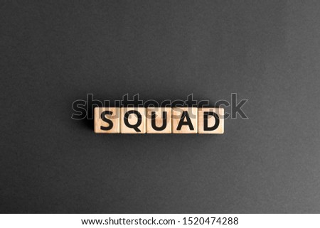 Squad - word from wooden blocks with letters, a team group of people work together concept, random letters around, top view gray background