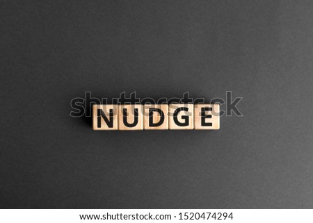 Nudge - word from wooden blocks with letters, pushing gently concept, random letters around, top view gray background Royalty-Free Stock Photo #1520474294