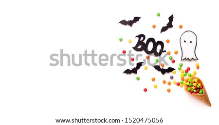 Halloween inspiration. Colored candies, ghost and bats flying out of the waffle horn on white background, panorama, copy space