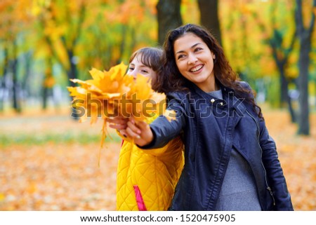 woman having fun with autumn leaves in city park, outdoor portrait