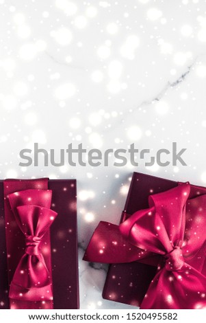New Years Eve celebration, wrapped luxury boxes and cold season concept - Winter holiday gifts with cherry silk bow and glowing snow on frozen marble background, Christmas presents surprise