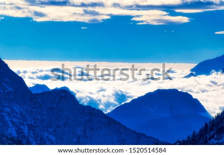 Austrian Alps under cloudy blue sky during cold winter day.