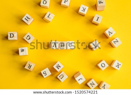 Wooden letters on yellow background to represent the alphabet  Royalty-Free Stock Photo #1520574221