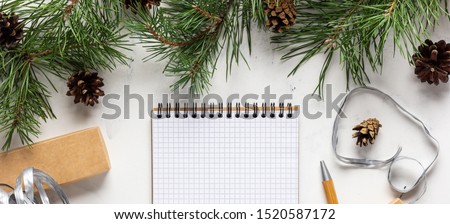 Christmas banner with a white marble background, pine branches and fir cones, a craft notebook or a squared sheet of paper for making a wish list or plans for the next new 2020 year. Place for text.