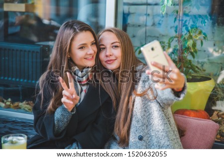 two pretty woman met in cafe taking selfie
