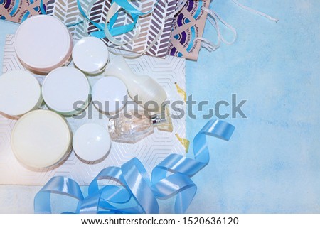 Sale, black friday, set of skin care creams and gift bags on a blue background, flat lay, top view. Concept of shopping and modern woman, place for text