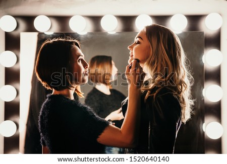 Young women doing makeup , old-fashioned. Stands near mirror. Backstage. Royalty-Free Stock Photo #1520640140