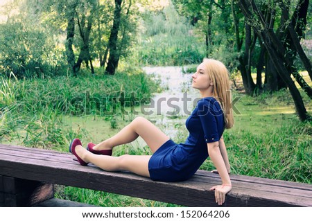 The girl sits on a bench in park