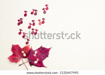 Red notes shoot out of two maple hearts. The concept of autumn sad music.