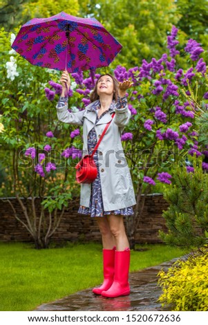 Beautiful woman with umbrella in the garden in the rain
