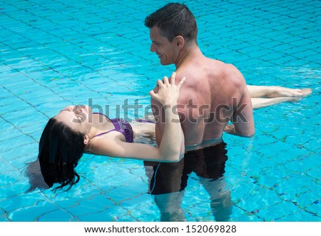 Young attractive couple in love in the water at swimming pool