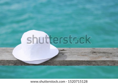 White Hat on the wood and Green space of the Sea background 