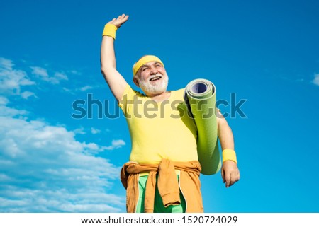 Hoppy Elderly man practicing sports on blue sky background. Healthy and sport. Sport and retirement concept. Grandfather sportsman. Happy Senior man exercising on blue sky