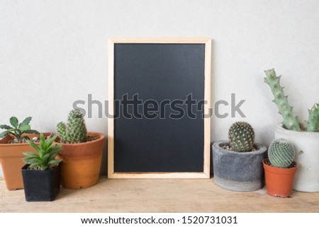 Blank chalkboard with cactus on wooden table. Mock up frame for your text