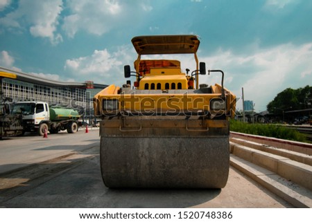 Road roller in the construction site with the construction of buildings and blue sky background.