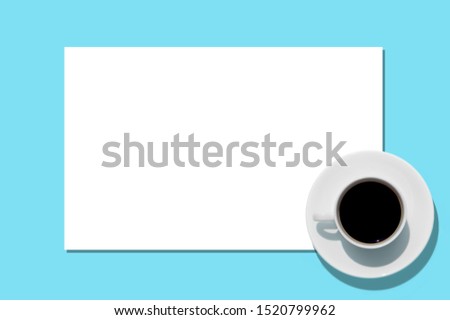 Cup with coffee on aquamarine background. Free space. Sheet of white paper. Top view.