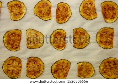 Keto zucchini chips resting on baking sheet after being baked in the oven.