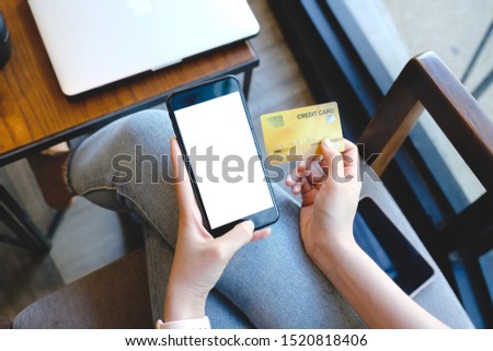 Close up of woman using blank cell phone and credit card sending massages shopping online on the coffee shop.