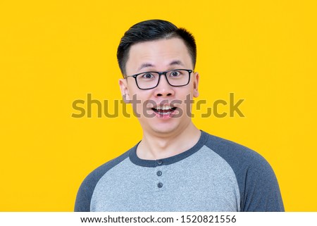 Close up portrait of shocked surprising young Asian man isolated on yellow background