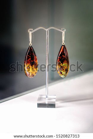 Amber earrings on a glass shelf. Close up.
