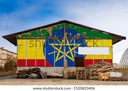 Close-up of the national flag of Ethiopia
 painted on the metal wall of a large warehouse the closed territory on a summer day. The concept of storage of goods, entry to a closed area, tourism