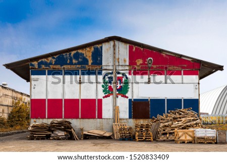 Close-up of the national flag of Dominicana painted on the metal wall of a large warehouse the closed territory on a summer day. The concept of storage of goods, entry to a closed area, tourism