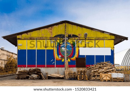 Close-up of the national flag of Ecuador
 painted on the metal wall of a large warehouse the closed territory on a summer day. The concept of storage of goods, entry to a closed area, tourism
