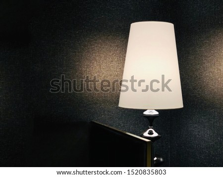 interior design warm white color lighting floor standing lamp with opal shade stands in front of matte black wallpaper which introduced warm welcome feeling for the hotel guests