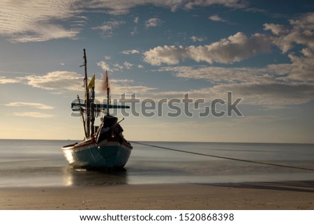 old beautiful fishing boat on beach , cloudy blue background , for background