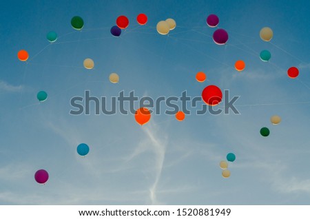 A lot of multi-colored balloons in the sky.