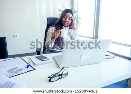 successful charming african american woman with purple hair in white shirt and gray pencil skirt sitting desk and write new startup project in a modern office with a panoramic window