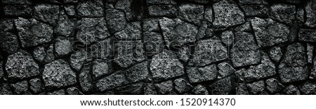 Natural granite stone wall wide texture. Dark rock masonry widescreen gloomy gothic background