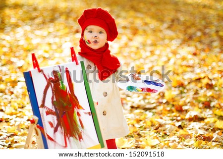 Child drawing on easel in Autumn Park. Creative kids development concept.