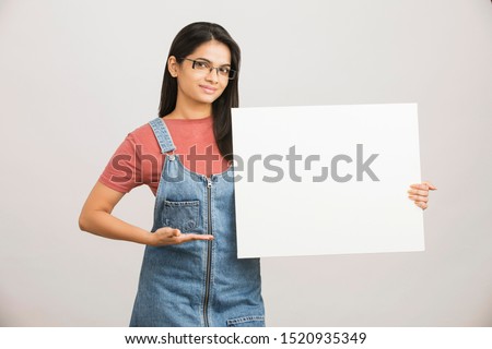 Pretty cheerful young Indian female holding white board.