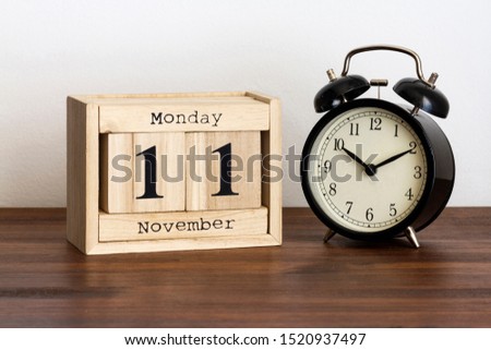 Wood calendar with date and old clock. Monday 11 November