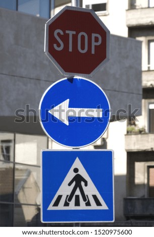 three traffic signs on one metal pole in the street