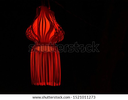 Hand made lantern emitting red light in black background. 