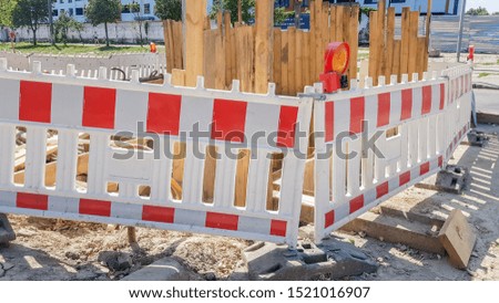 Plastic Protective barrier fences the site of road work. Red and white plastic fence near the street repair site. Construction work on the street, road repair, protective fence